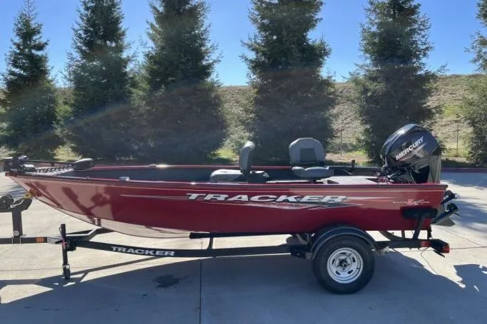 The Image of 2025 Tracker Super Guide V-16 T boat, red, on trailer, outdoors. - 0
