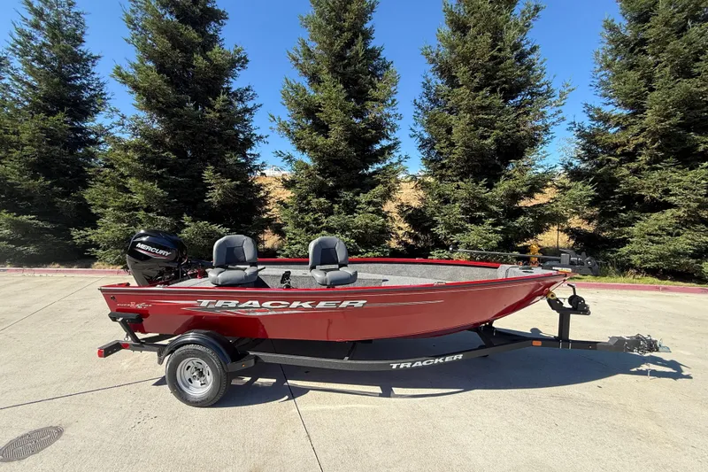 The Image of 2025 Tracker Super Guide V-16 T boat on trailer, parked outdoors with trees in background. - 0