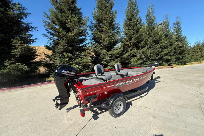 Slide: The Image of 2025 Tracker Super Guide V-16 T boat with Mercury engine, parked outdoors near trees. - 3