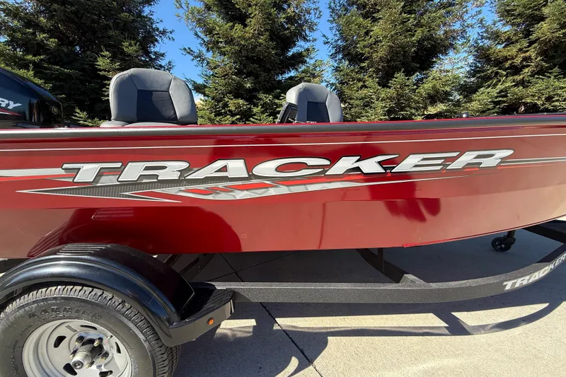 Slide: The Image of 2025 Tracker Super Guide V-16 T boat, red exterior, parked on trailer, outdoor setting. - 9