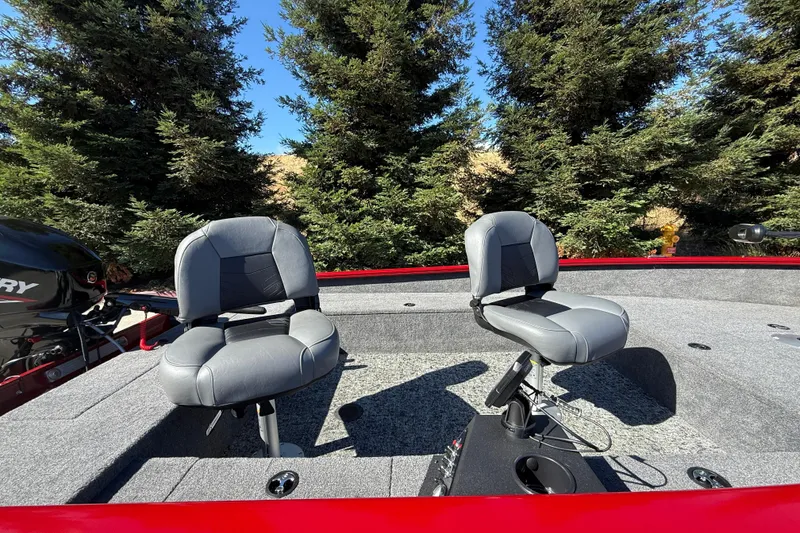 Slide: The Image of 2025 Tracker Super Guide V-16 T boat interior with two gray seats, surrounded by trees. - 15