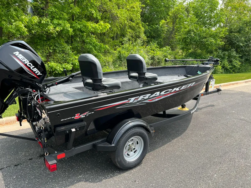 Slide: The Image of 2025 Tracker Super Guide V-16 T boat on trailer, parked on asphalt near greenery. - 3