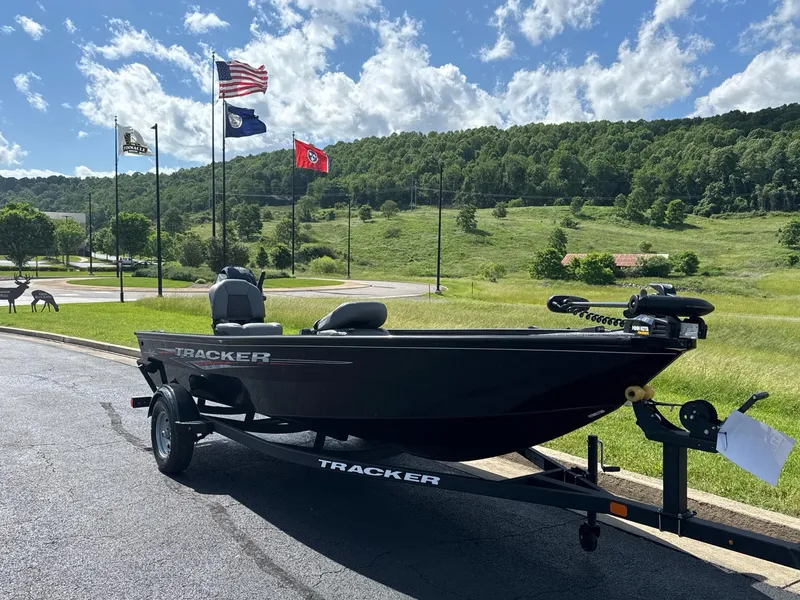 Slide: The Image of 2025 Tracker Super Guide V-16 T boat on trailer, scenic background with flags and hills. - 2