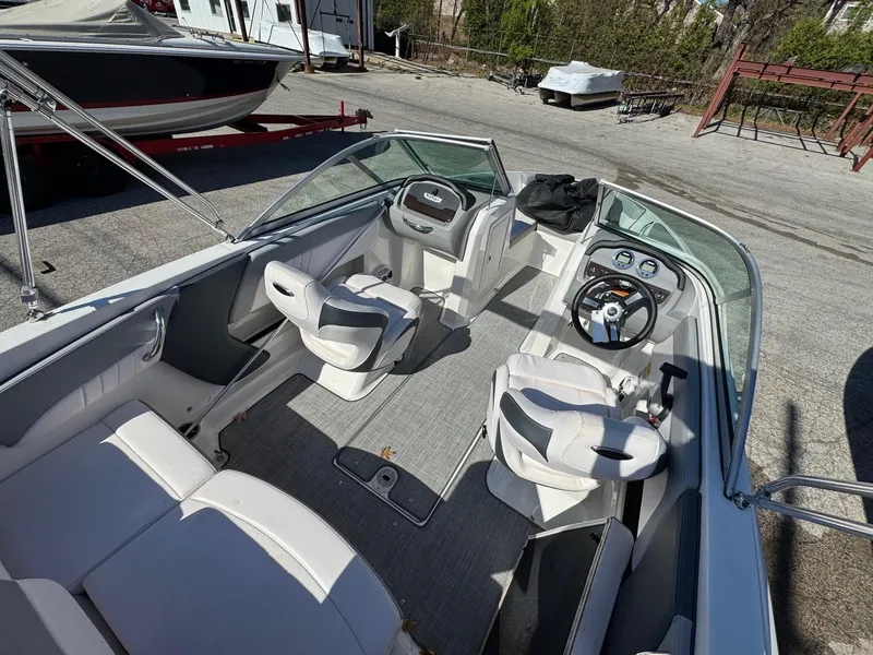 Slide: The Image of 2020 Chaparral 19 SSi OB boat interior with seating and steering wheel, parked outdoors. - 10