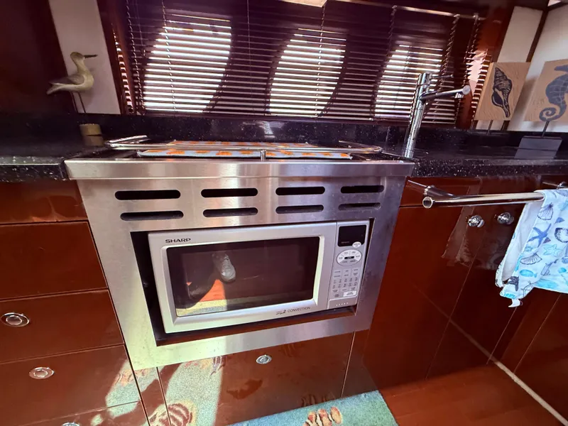 Slide: The Image of 2009 Sea Ray 48 Sundancer kitchen with stainless steel microwave and wooden cabinetry. - 28