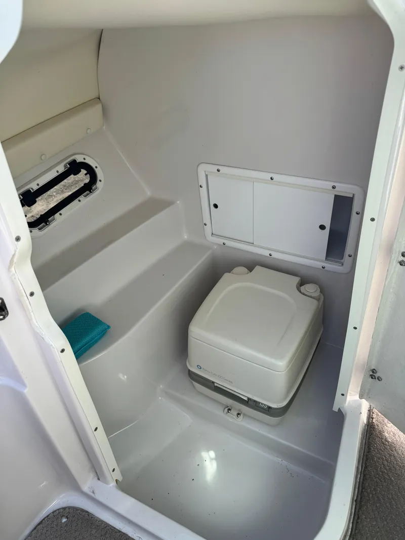Slide: The Image of 2004 Four Winns 250 Horizon boat interior with compact toilet and storage area. - 15