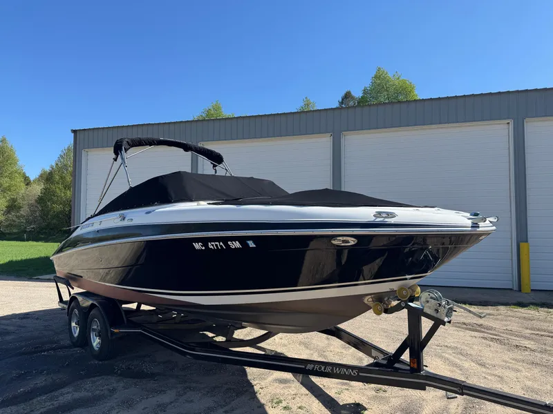 Slide: The Image of 2004 Four Winns 250 Horizon boat on trailer, parked outdoors near storage facility. - 2