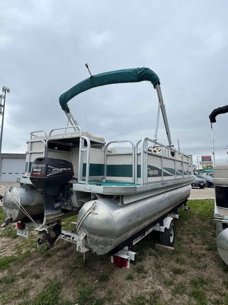 Slide: The Image of 1996 Premier Odyessea pontoon boat with canopy and outboard motor, parked on grass. - 1
