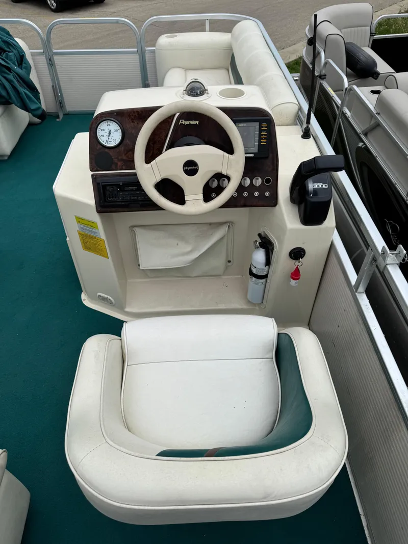 Slide: The Image of 1996 Premier Odyessea boat dashboard with steering wheel and controls, featuring white seating. - 11