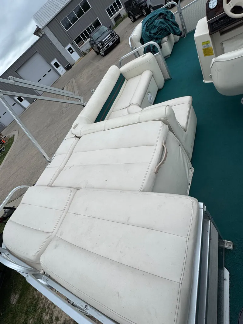 Slide: The Image of 1996 Premier Odyessea boat with white seating and teal flooring, parked near a building. - 13