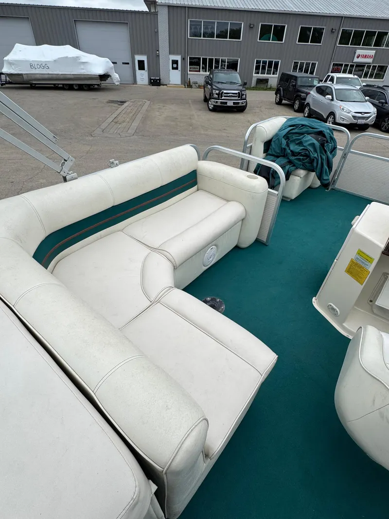 Slide: The Image of 1996 Premier Odyessea boat with white seating and teal carpet, parked near a garage. - 16