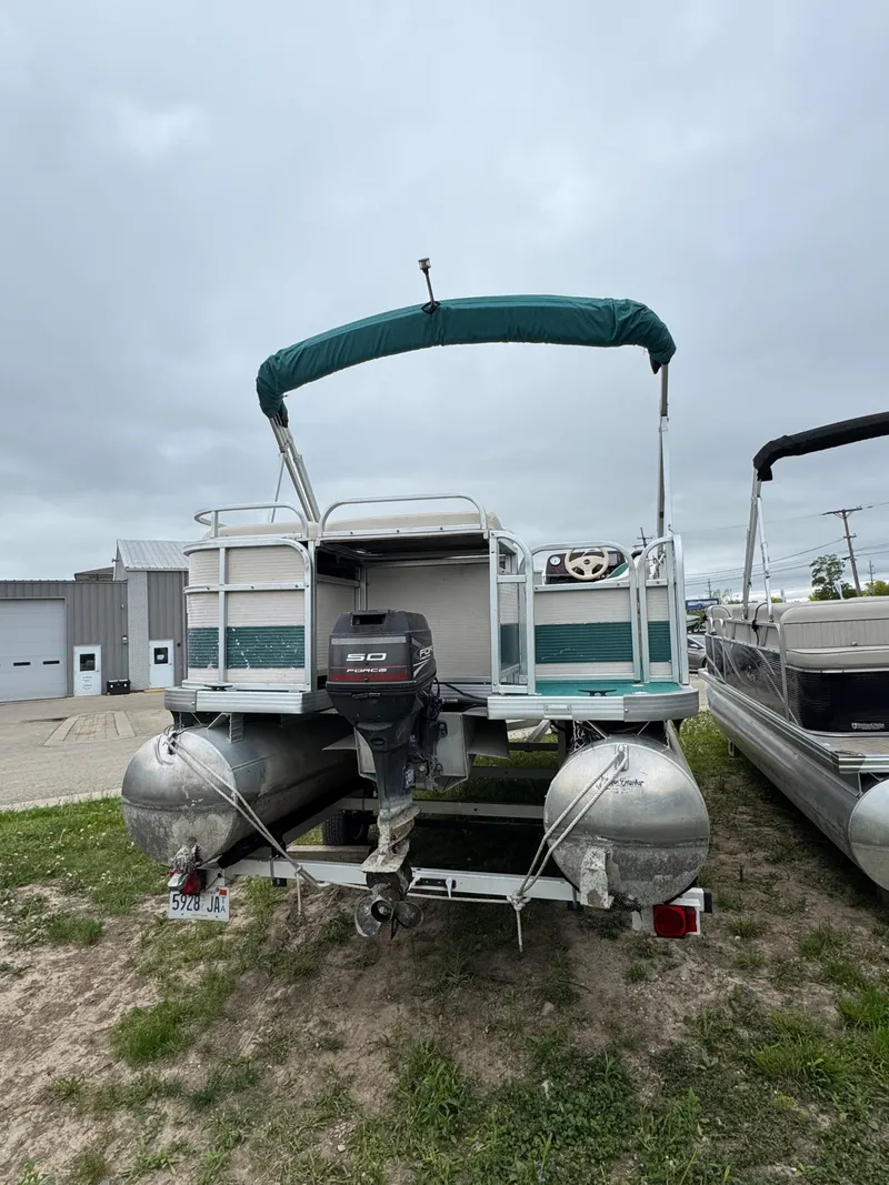 Slide: The Image of 1996 Premier Odyessea pontoon boat with canopy and outboard motor, parked on grass. - 2
