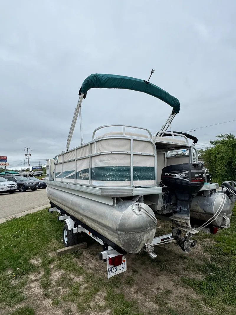 Slide: The Image of 1996 Premier Odyessea pontoon boat with canopy and outboard motor, parked on grass. - 5