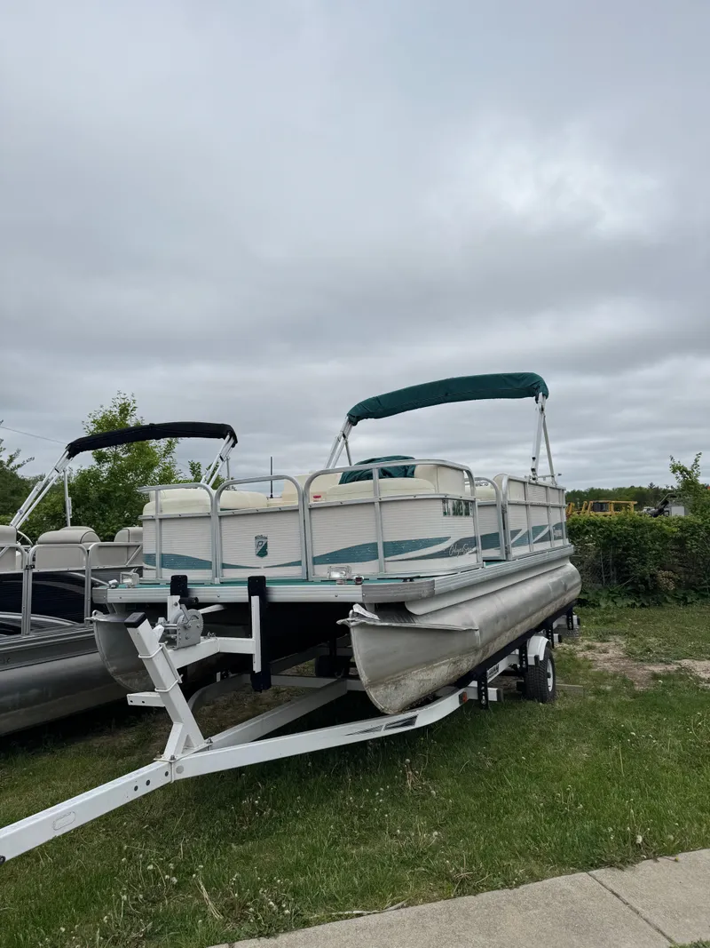 Slide: The Image of 1996 Premier Odyessea pontoon boat on trailer, parked on grass under cloudy sky. - 6
