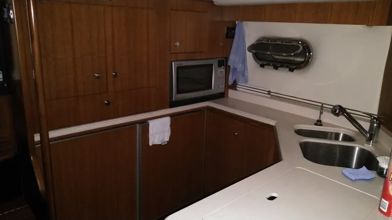 Slide: The Image of 2005 Tiara Yachts 4400 Sovran kitchen with wood cabinetry, sink, and microwave. - 25
