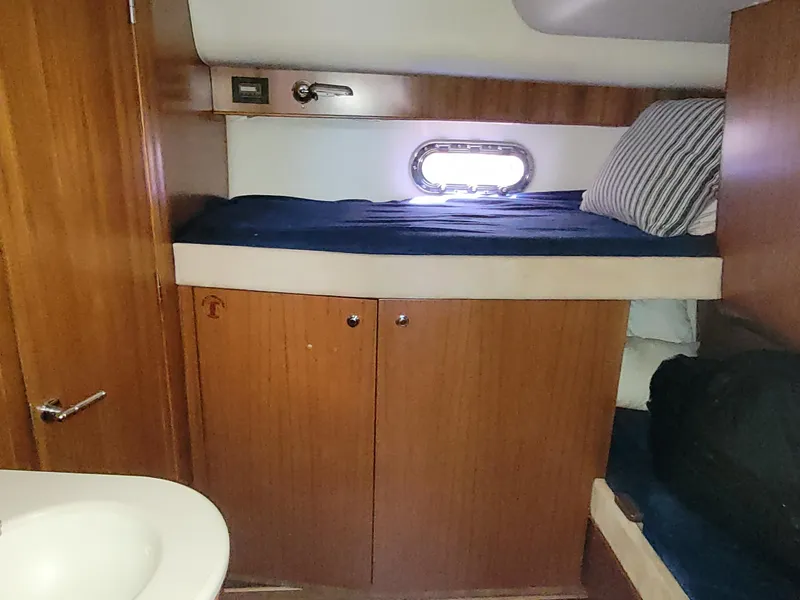 Slide: The Image of 2005 Tiara Yachts 4400 Sovran cabin interior with wooden cabinetry and cozy bedding. - 40