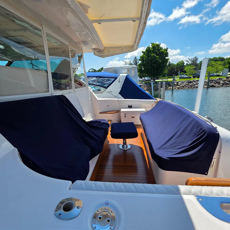 Slide: The Image of 2005 Tiara Yachts 4400 Sovran with covered seating, docked by a scenic waterfront. - 48