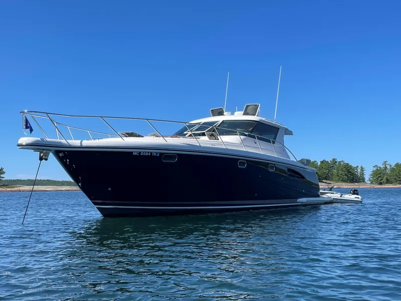 Slide: The Image of 2005 Tiara Yachts 4400 Sovran docked by a serene lake under clear blue skies. - 5