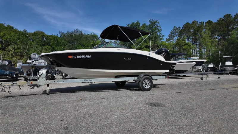 Slide: The Image of 2018 Sea Ray 190 Bow Rider boat on trailer, parked outdoors under clear blue sky. - 10