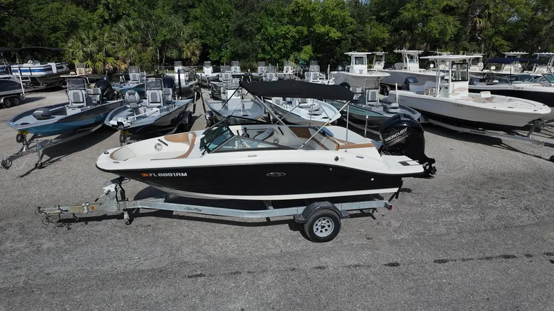 Slide: The Image of 2018 Sea Ray 190 Bow Rider boat on trailer, surrounded by other boats in a marina. - 18