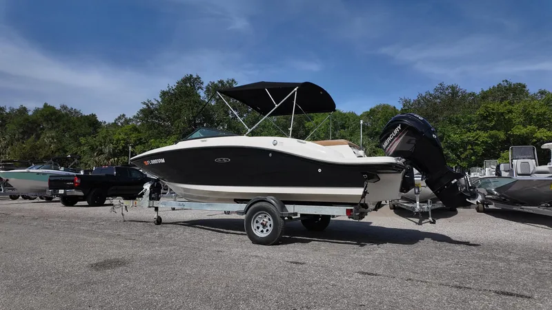 Slide: The Image of 2018 Sea Ray 190 Bow Rider boat on trailer in parking lot, under clear blue sky. - 26