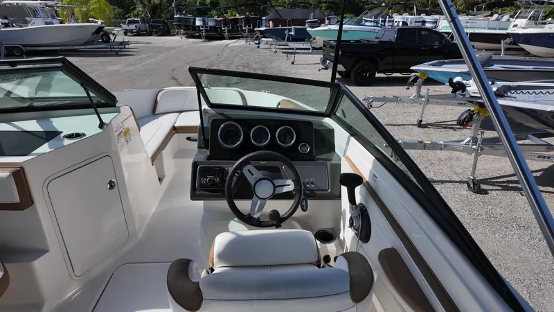 Slide: The Image of 2018 Sea Ray 190 Bow Rider interior with steering wheel and dashboard, parked in a marina. - 29