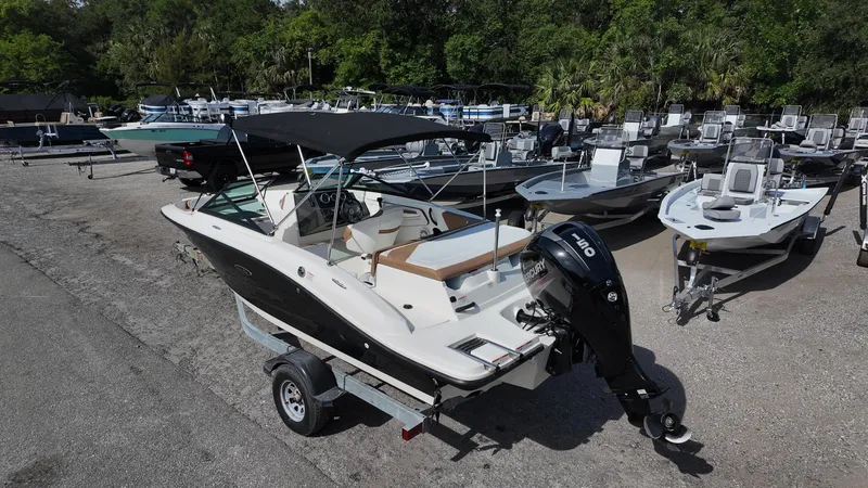 Slide: The Image of 2018 Sea Ray 190 Bow Rider boat on trailer, surrounded by other boats in a marina. - 32