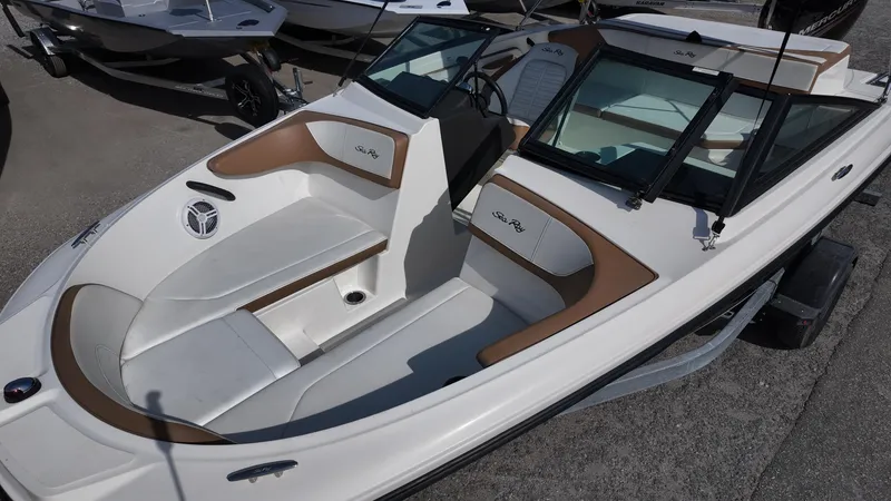 Slide: The Image of 2018 Sea Ray 190 Bow Rider boat with white and brown interior, docked on a trailer. - 9