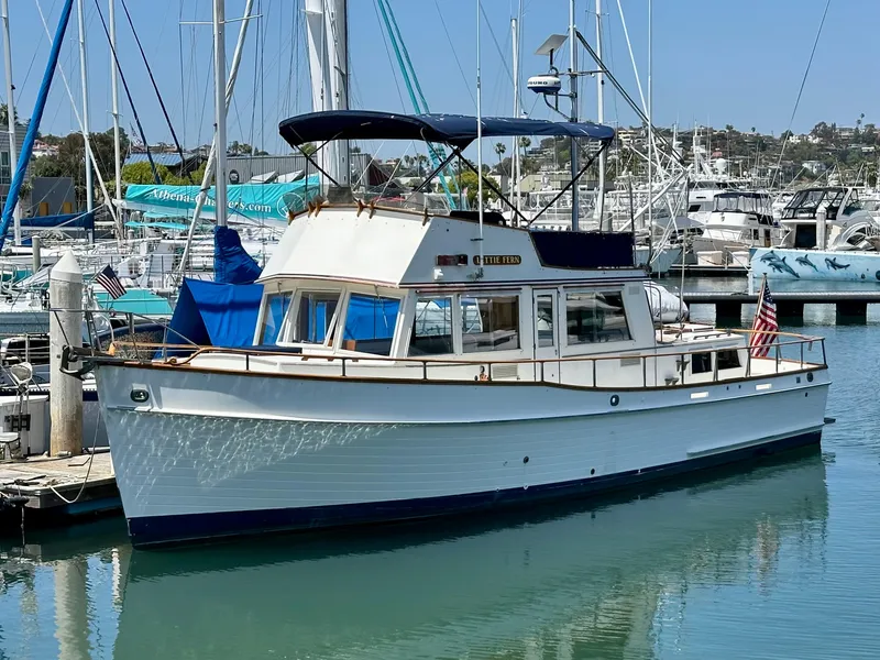 The Image of 1977 Grand Banks 42 Classic yacht docked in a marina, featuring a white hull and blue canopy. - 0