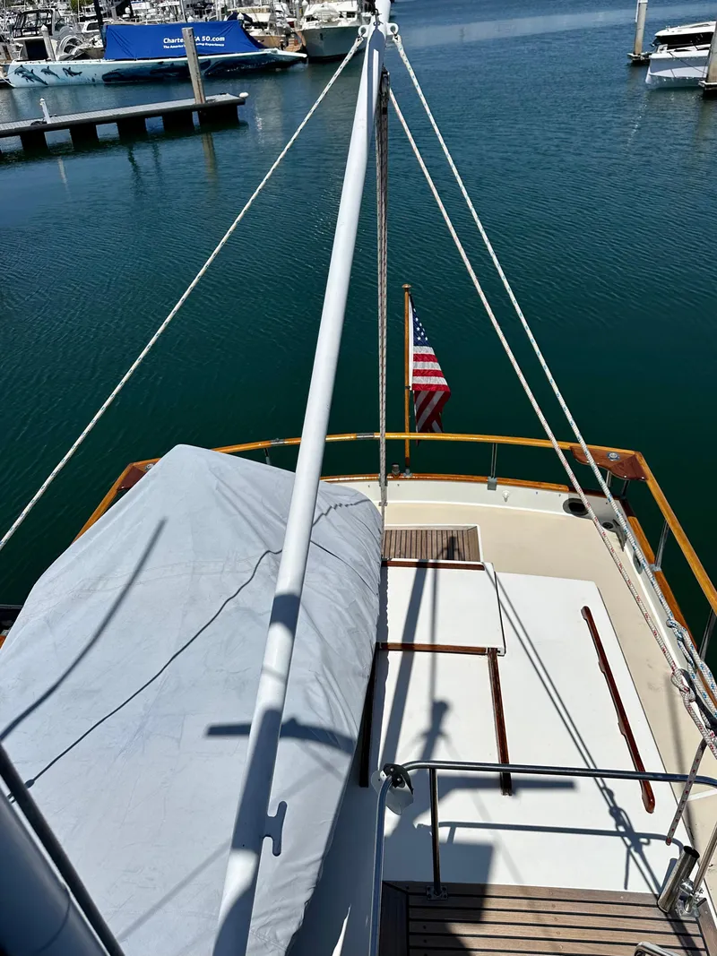 Slide: The Image of 1977 Grand Banks 42 Classic yacht docked in a marina, featuring a covered deck and American flag. - 11