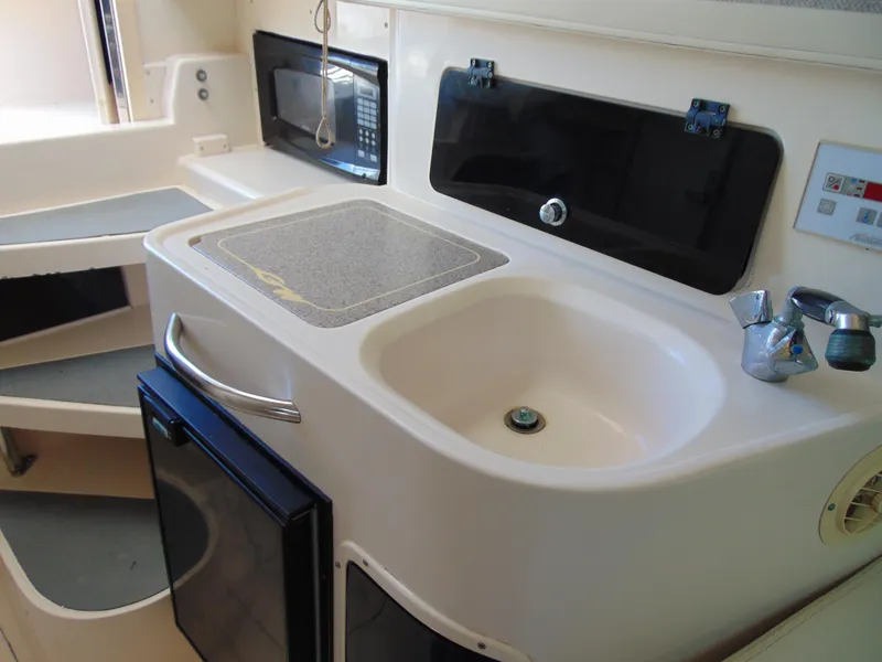 Slide: The Image of 2002 Grady-White 30 Marlin WA boat kitchen with sink, stove, and microwave. - 23