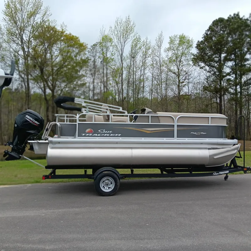 The Image of 2025 Sun Tracker Party Barge 18 DLX pontoon boat on trailer, parked outdoors. - 0