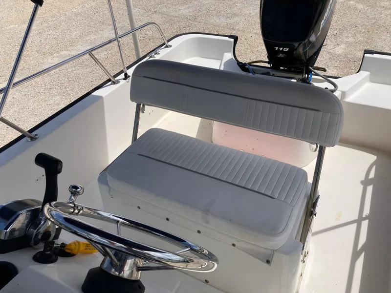 Slide: The Image of 2005 Boston Whaler 170 Montauk boat interior with steering wheel and cushioned seating. - 12