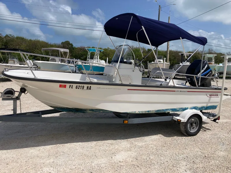Slide: The Image of 2005 Boston Whaler 170 Montauk boat on trailer with blue canopy, parked outdoors. - 5