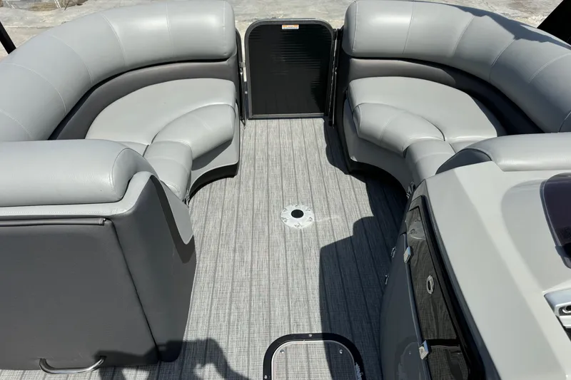 Slide: The Image of 2020 Manitou Oasis SR boat interior with gray seating and textured flooring. - 10