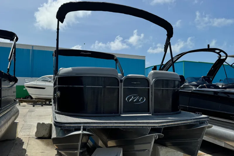 Slide: The Image of 2020 Manitou Oasis SR pontoon boat with canopy, docked under a clear blue sky. - 17