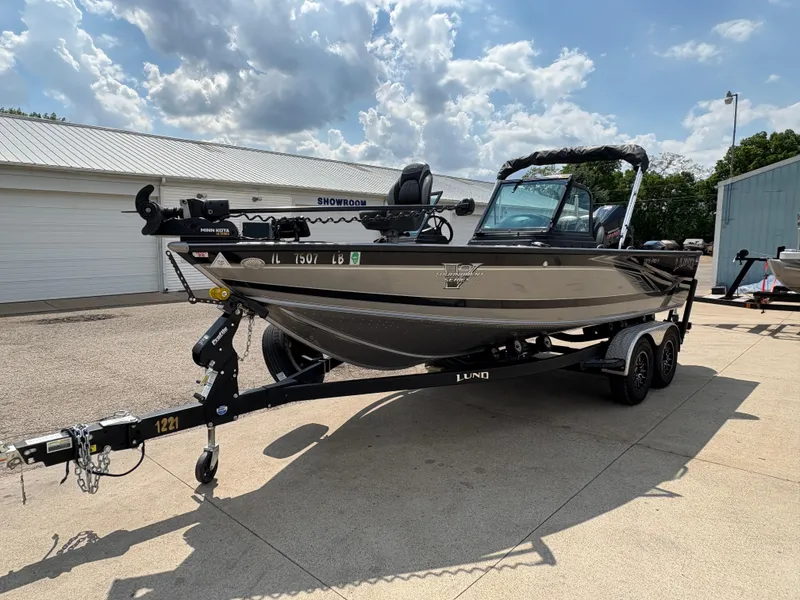 Slide: The Image of 2021 Lund 1975 Pro-V boat on trailer, parked outdoors under a cloudy sky. - 13
