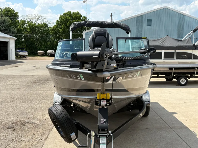 Slide: The Image of 2021 Lund 1975 Pro-V boat on trailer, parked outdoors near a warehouse. - 15