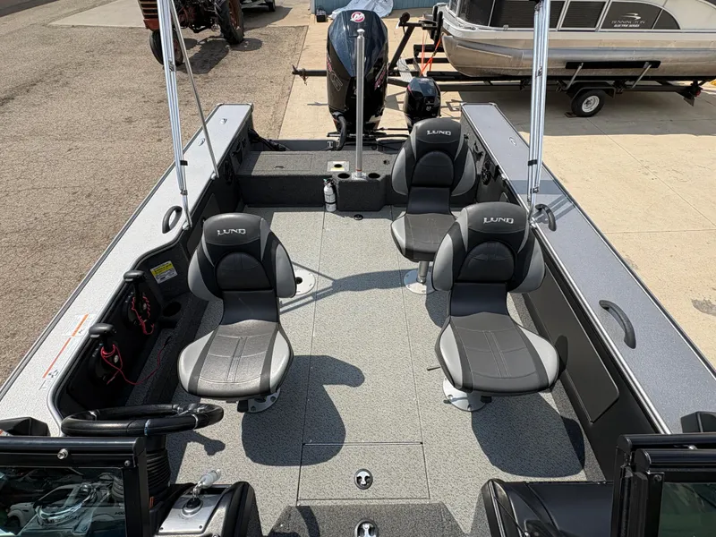 Slide: The Image of 2021 Lund 1975 Pro-V boat interior with four seats and motor, docked on pavement. - 29