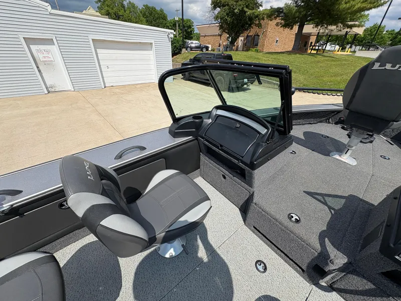 Slide: The Image of 2021 Lund 1975 Pro-V boat interior with gray seating and dashboard, parked outdoors. - 32