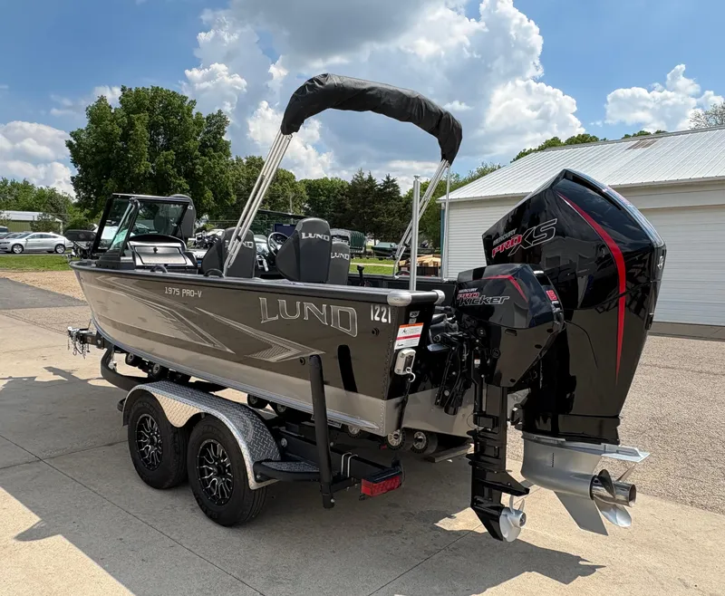 Slide: The Image of 2021 Lund 1975 Pro-V boat on trailer, parked outdoors under a cloudy sky. - 9