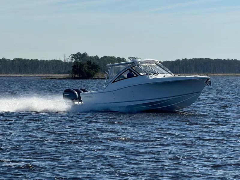 Slide: The Image of 2025 Albemarle 31 Dual Console boat on water, with coastal homes in the background. - 2