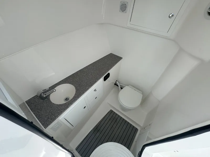 Slide: The Image of 2025 Albemarle 31 Dual Console boat bathroom with sink, toilet, and storage cabinets. - 24