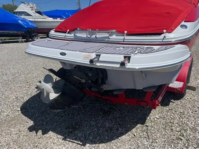 Slide: The Image of 2007 Crownline 240 EX boat with red cover, rear view showing propeller and trailer. - 4
