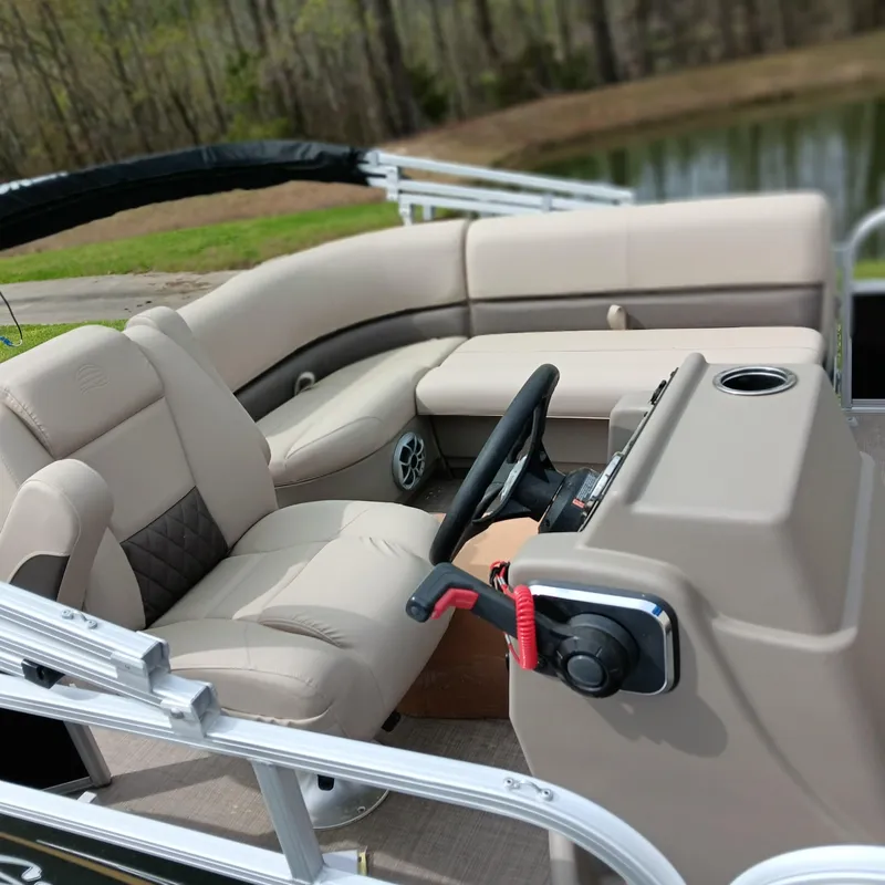 Slide: The Image of 2025 Sun Tracker Party Barge 16 DLX interior with beige seating and steering console. - 10