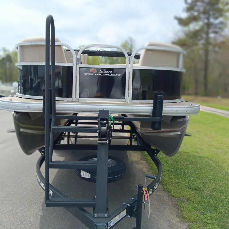 Slide: The Image of 2025 Sun Tracker Party Barge 16 DLX on trailer, parked on a road. - 5