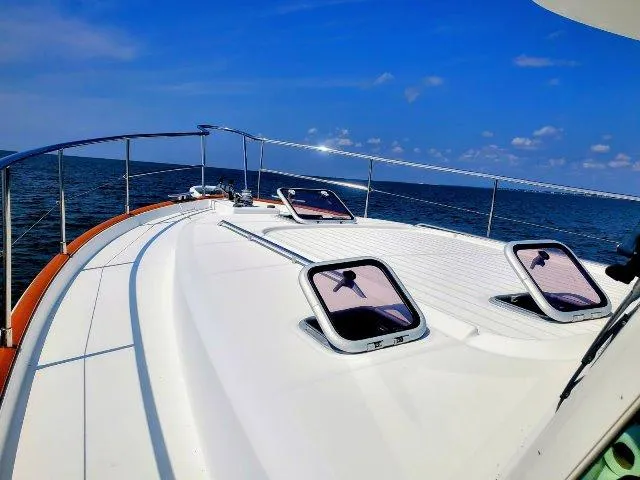 Slide: The Image of 2006 Beneteau Swift Trawler 42 on open sea, showcasing deck and hatches under clear blue sky. - 10