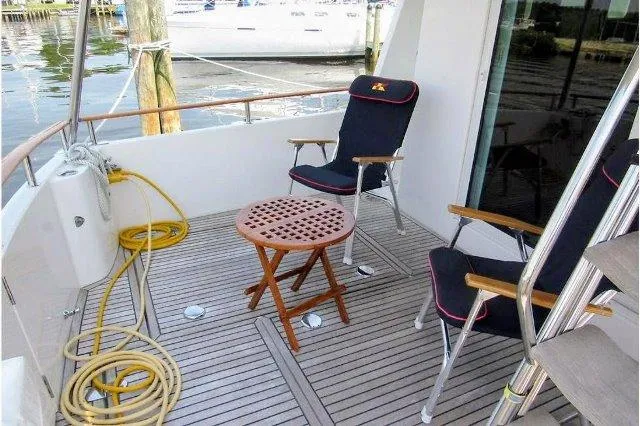 Slide: The Image of 2006 Beneteau Swift Trawler 42 deck with chairs and table, docked by water. - 23