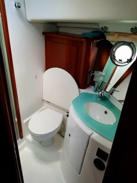 Slide: The Image of 2006 Beneteau Swift Trawler 42 bathroom with toilet, sink, and porthole window. - 41