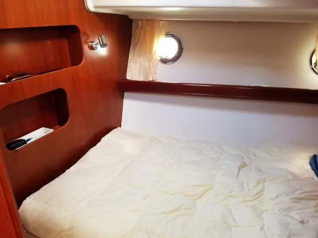 Slide: The Image of Cozy cabin interior of 2006 Beneteau Swift Trawler 42 with wooden shelves and porthole. - 46
